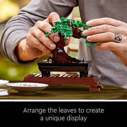 Person assembling LEGO® Bonsai Tree model with interchangeable leaves for a unique display.