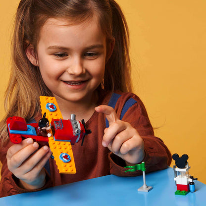 Child building with LEGO® Disney Mickey Mouse Plane Set 10772, featuring airplane and minifigure, promoting creativity and play.
