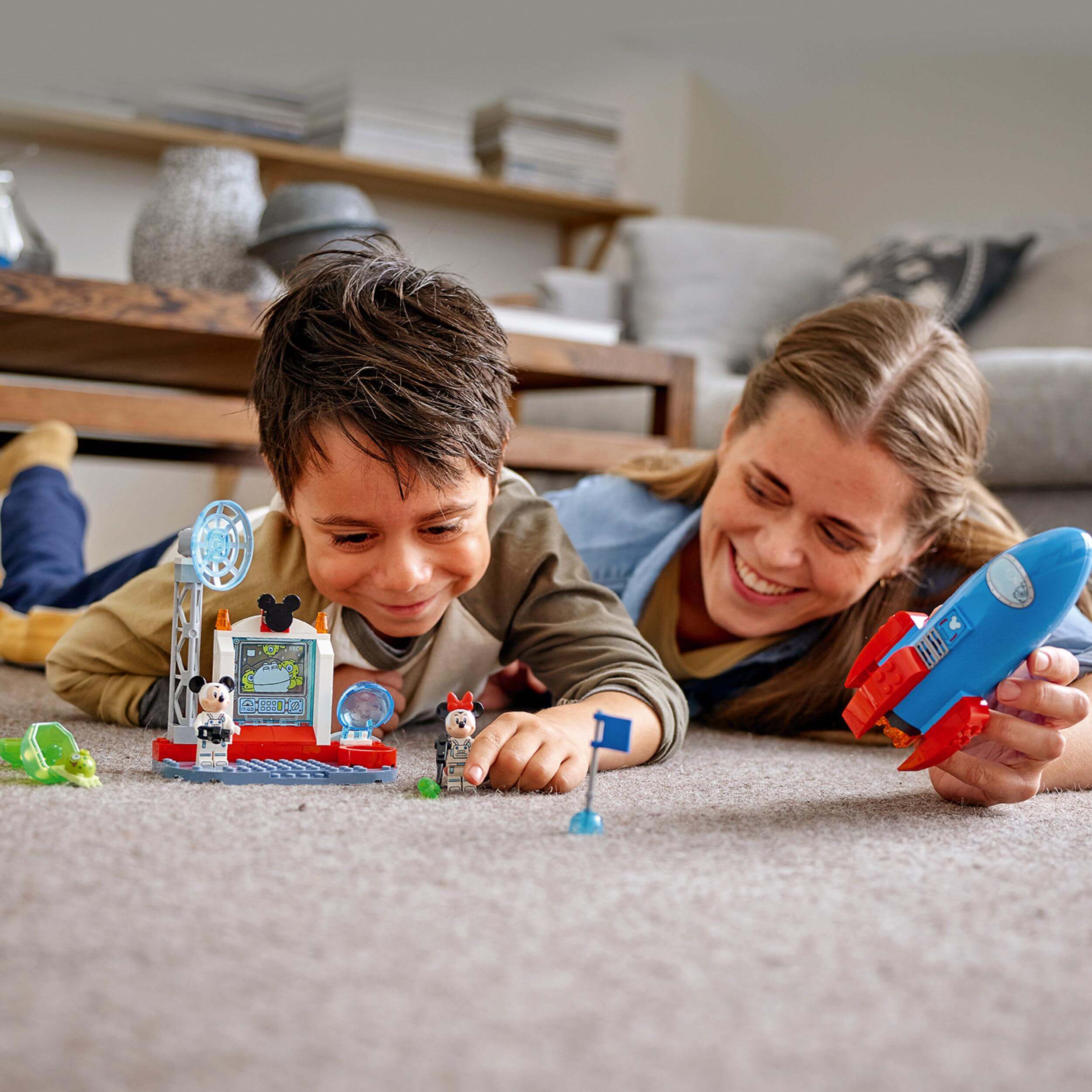 Kid and adult enjoying LEGO Disney Mickey & Minnie Mouse Space Rocket playset with rocket and minifigures.