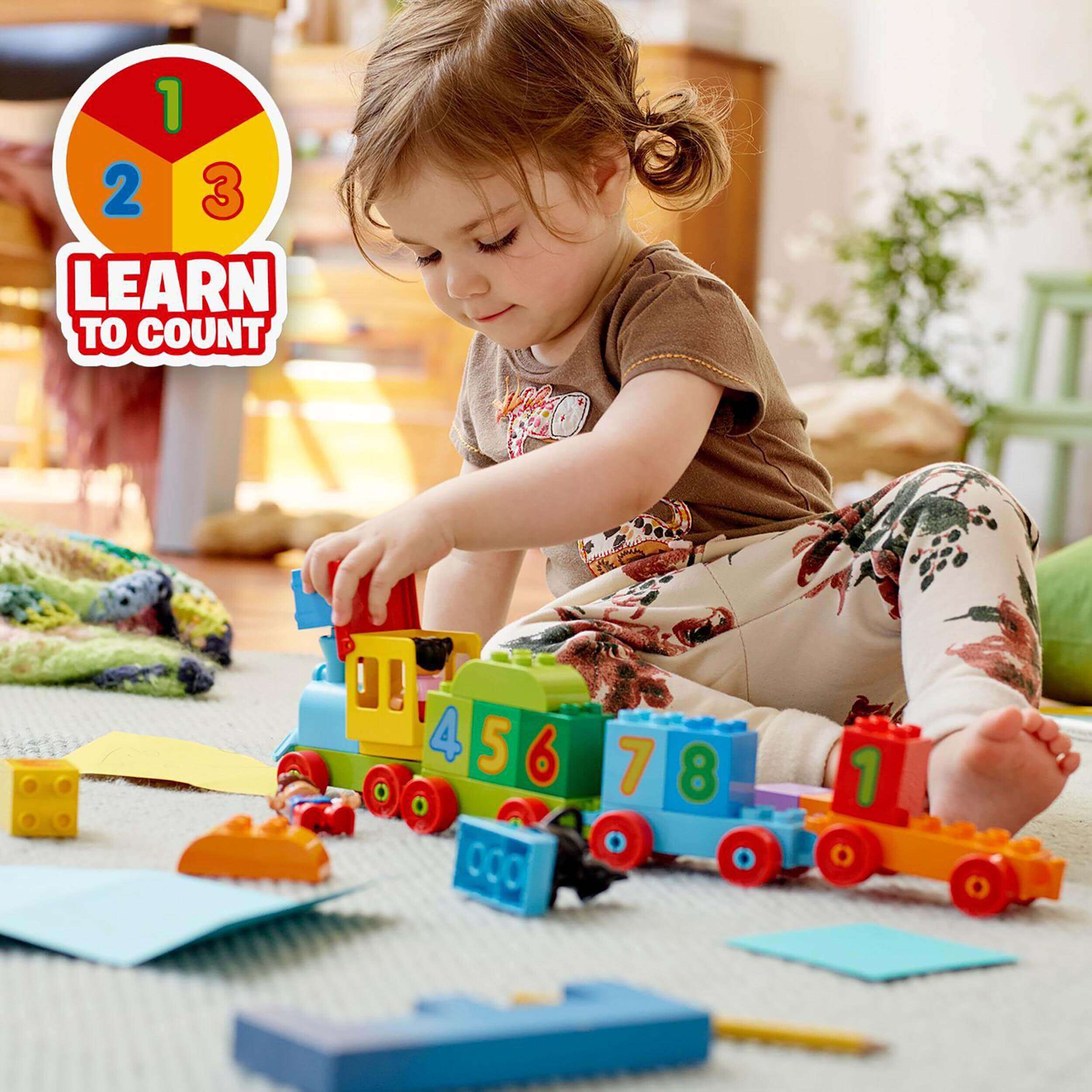 Child playing with LEGO DUPLO Number Train set 10847, learning to count and recognize numbers with colorful train blocks.