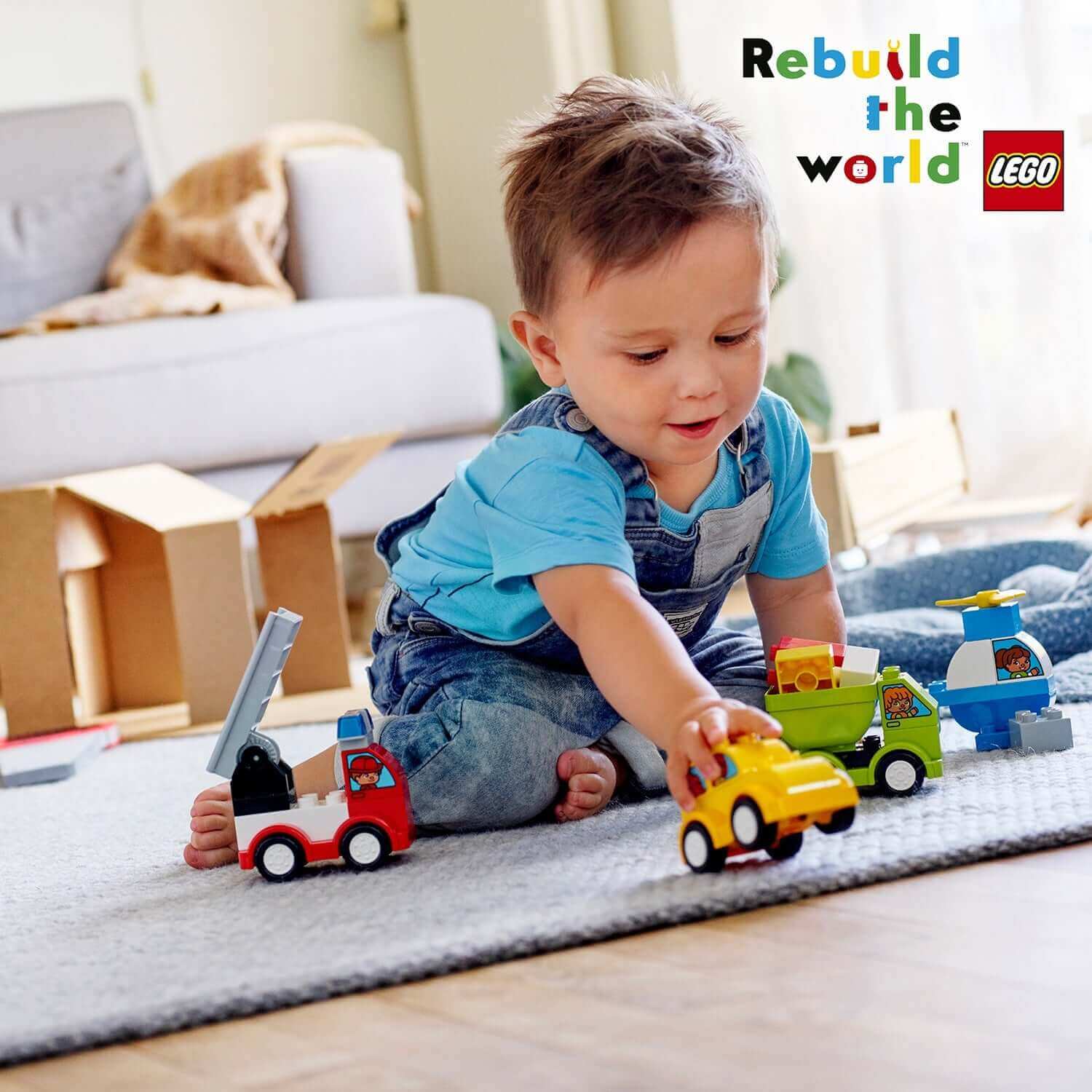 Toddler playing with LEGO® DUPLO My First Car Creations set featuring colorful trucks and cars on a play mat.