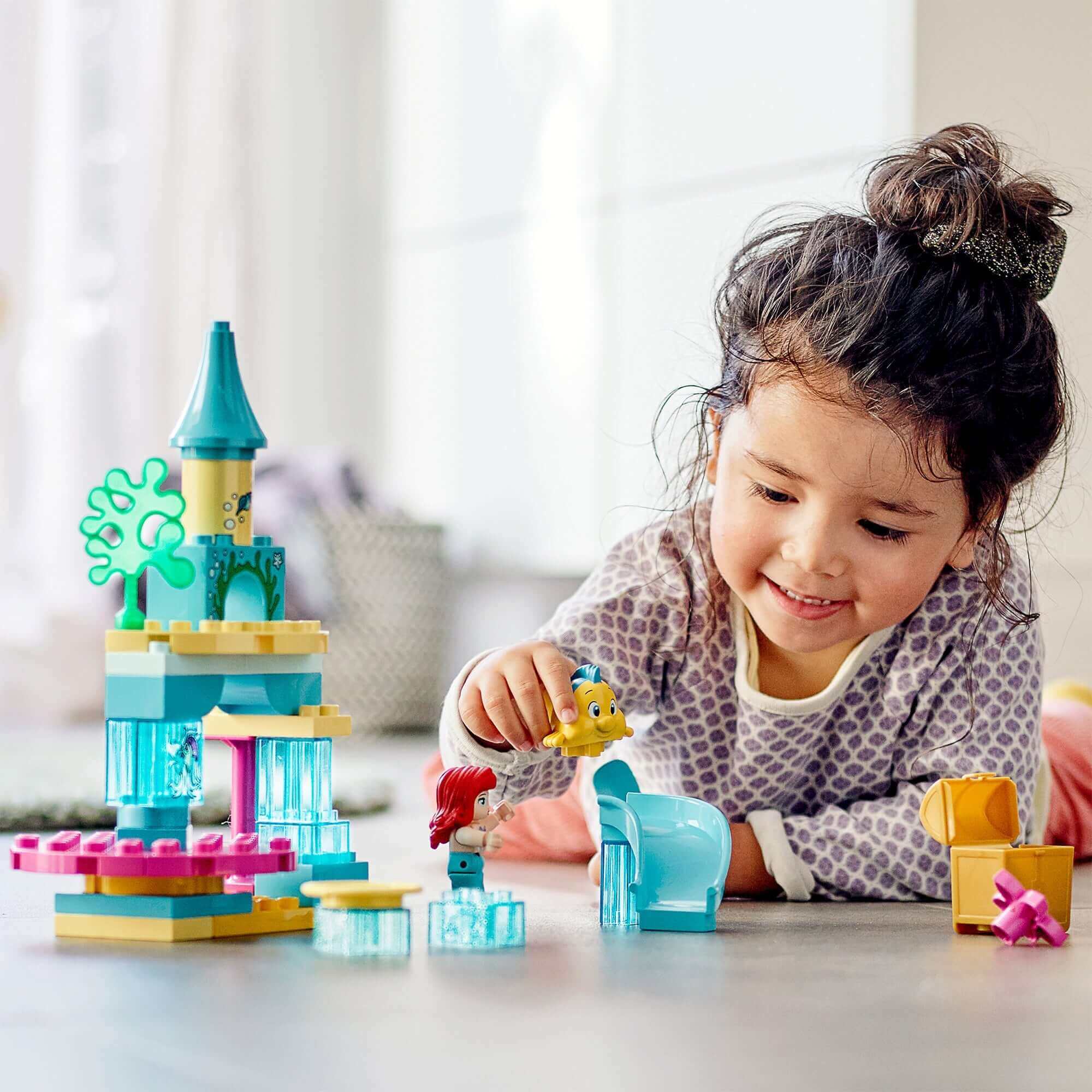 Child playing with LEGO® DUPLO Princess Ariel Undersea Castle Set 10922, featuring Ariel and Flounder.