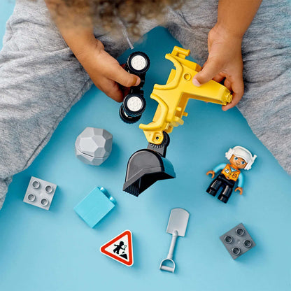 Child playing with LEGO® DUPLO Bulldozer, colorful building blocks, and accessories on a blue surface.