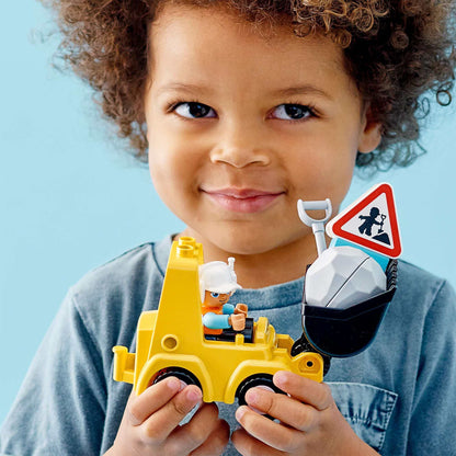 Toddler holding LEGO® DUPLO Bulldozer Toy Truck 10930, engaging in fun and creative play.