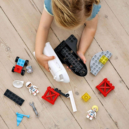 Child playing with LEGO® DUPLO Space Shuttle Mission set, featuring shuttle, astronauts, and colorful building pieces.