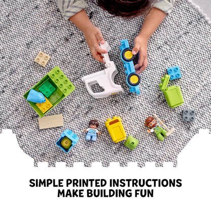 Child playing with LEGO DUPLO recycling truck set, featuring colorful blocks and simple instructions on a play mat.