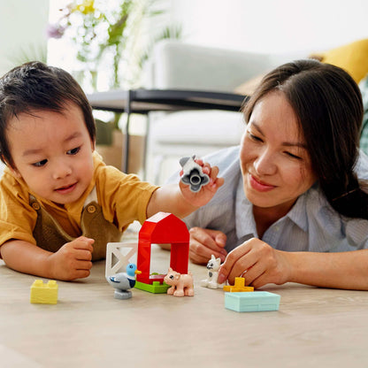 Toddler playing with LEGO DUPLO Town Farm Animal Care set, engaging with farm animals and mother guiding creative play.