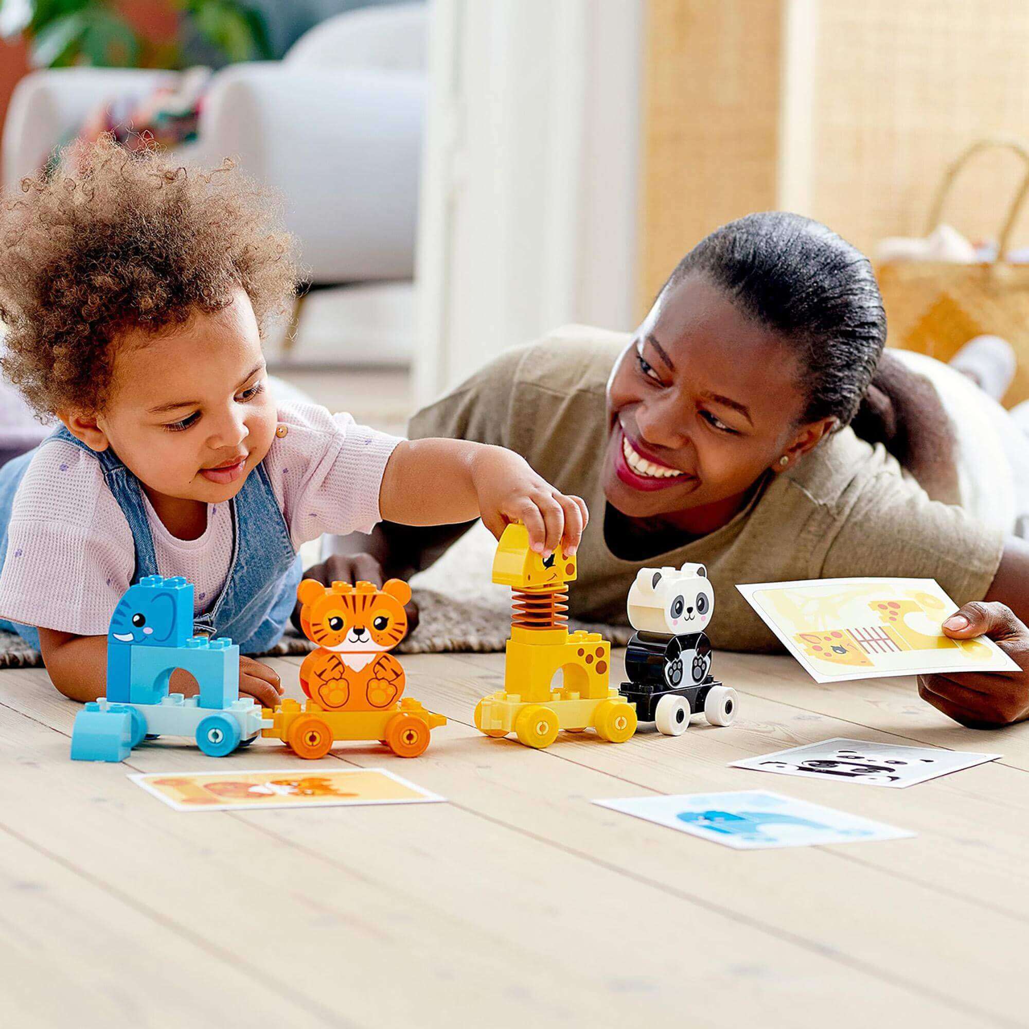 A child and a parent playing with LEGO® DUPLO My First Animal Train Toy, featuring colorful animal figures and educational activities.