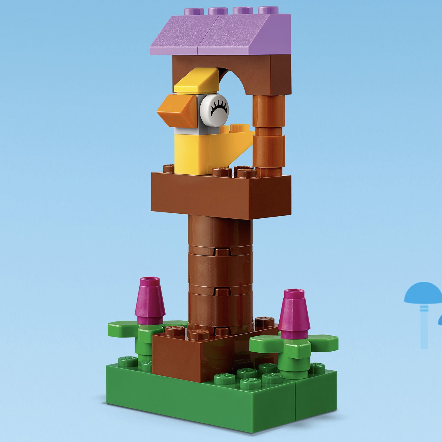 Colorful LEGO® birdhouse with a yellow bird, flowers, and green base, showcasing creativity with construction toy 11002.