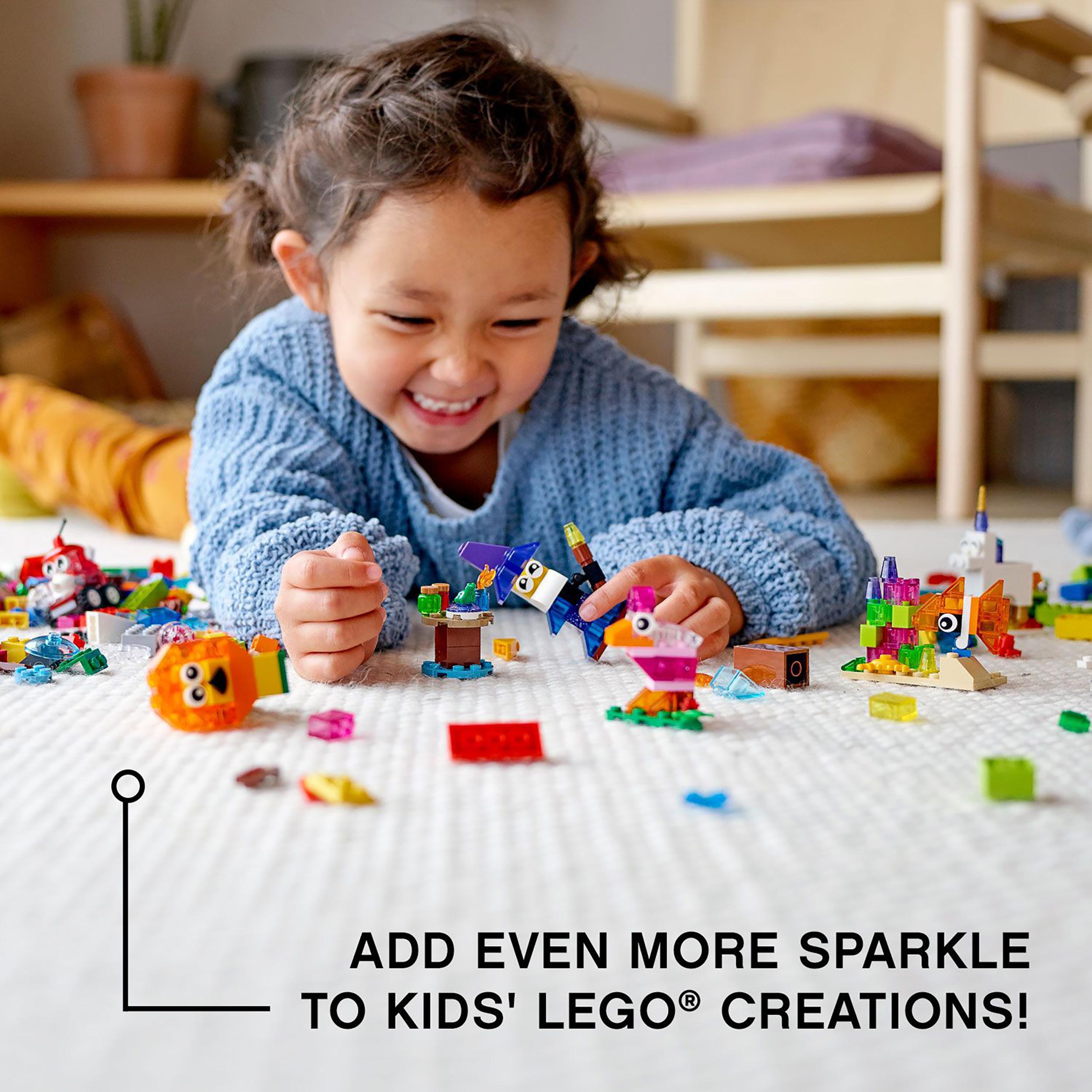 Child playing with LEGO® Classic Creative Transparent Bricks Set 11013, adding sparkle to imaginative builds.