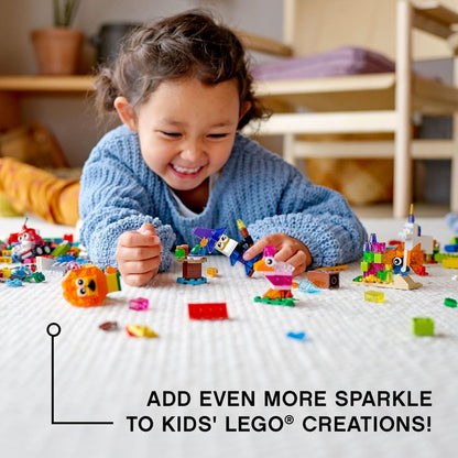 Child playing with LEGO® Classic Creative Transparent Bricks Set 11013, adding sparkle to imaginative builds.