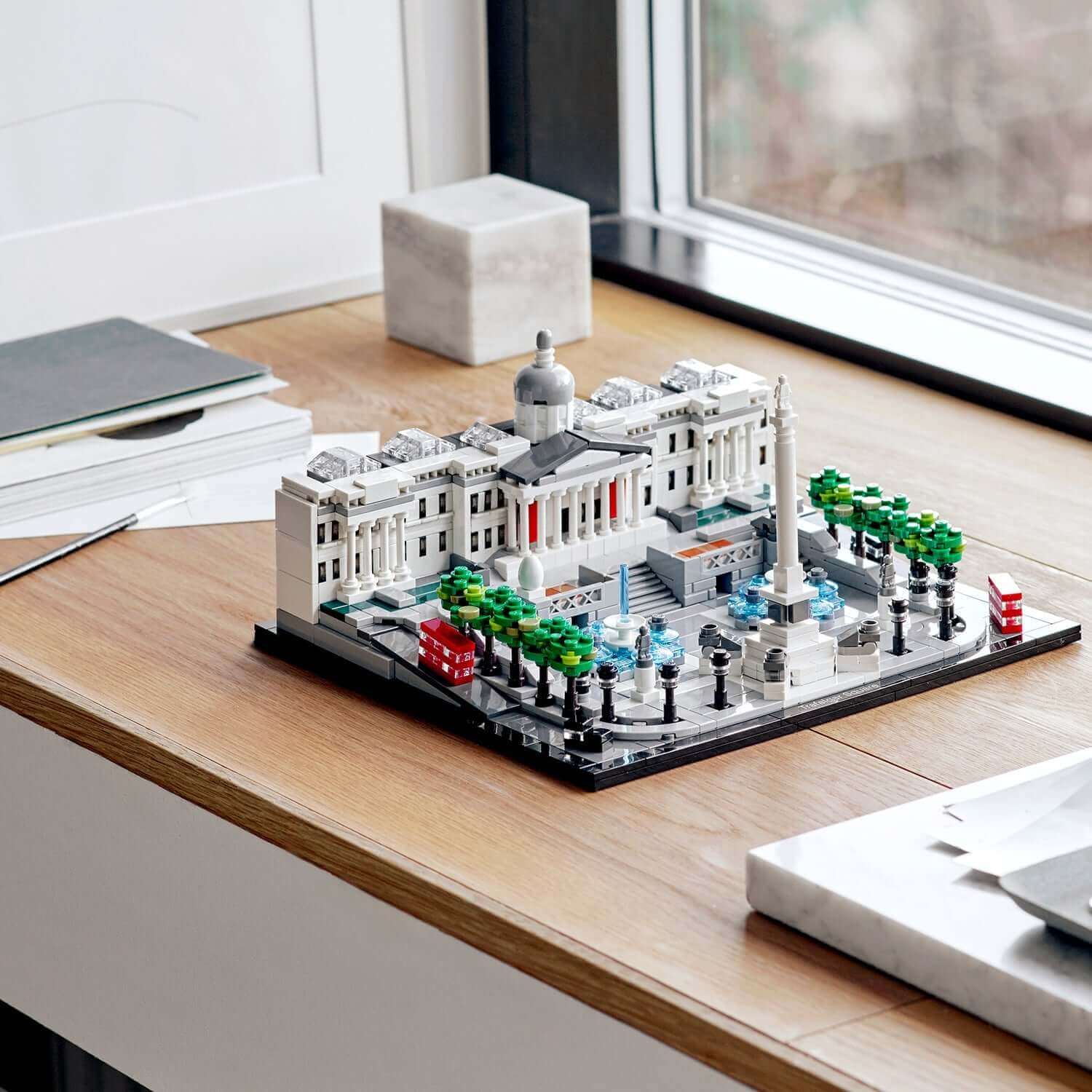 LEGO® Architecture Trafalgar Square set 21045 displayed on a wooden table with greenery and iconic British elements.