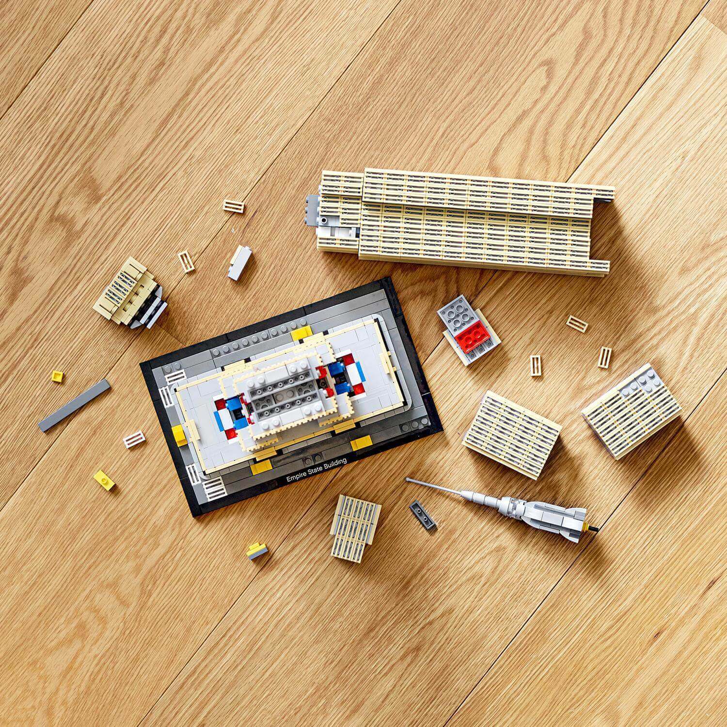 LEGO® Architecture Empire State Building set 21046 with building pieces and instruction manual on a wooden surface.