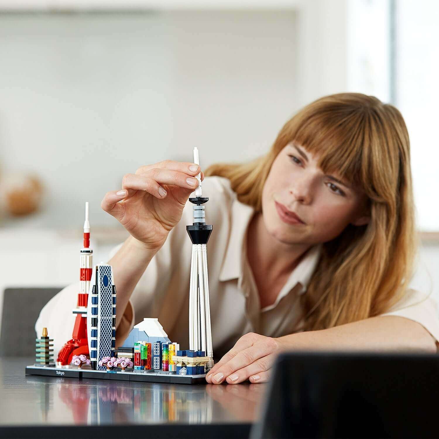 Adult building the LEGO® Architecture Tokyo Skyline Set 21051, showcasing Tokyo landmarks with creativity.
