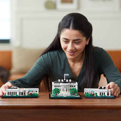 Woman assembling LEGO® Architecture The White House Building Set 21054 on a wooden table, showcasing her DIY project.