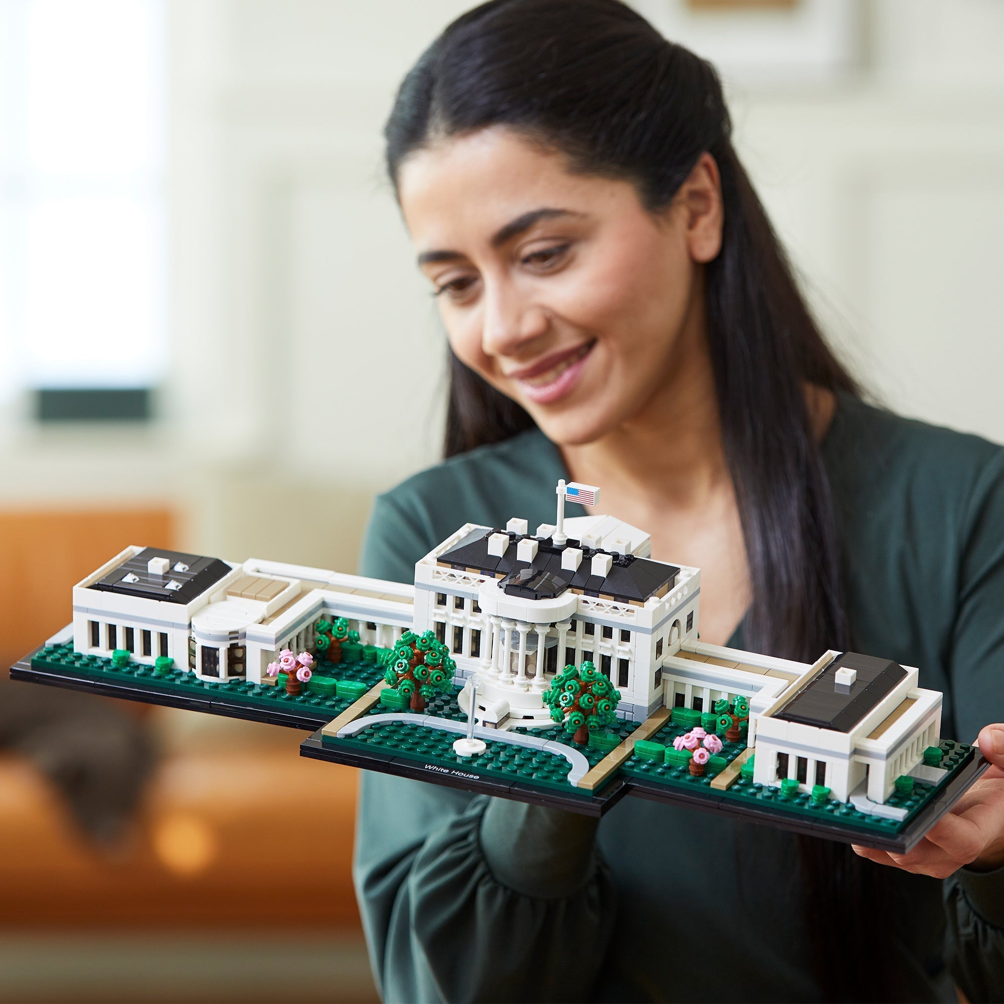 Woman showcasing LEGO Architecture The White House Building Set 21054, a detailed DIY model of the iconic landmark.