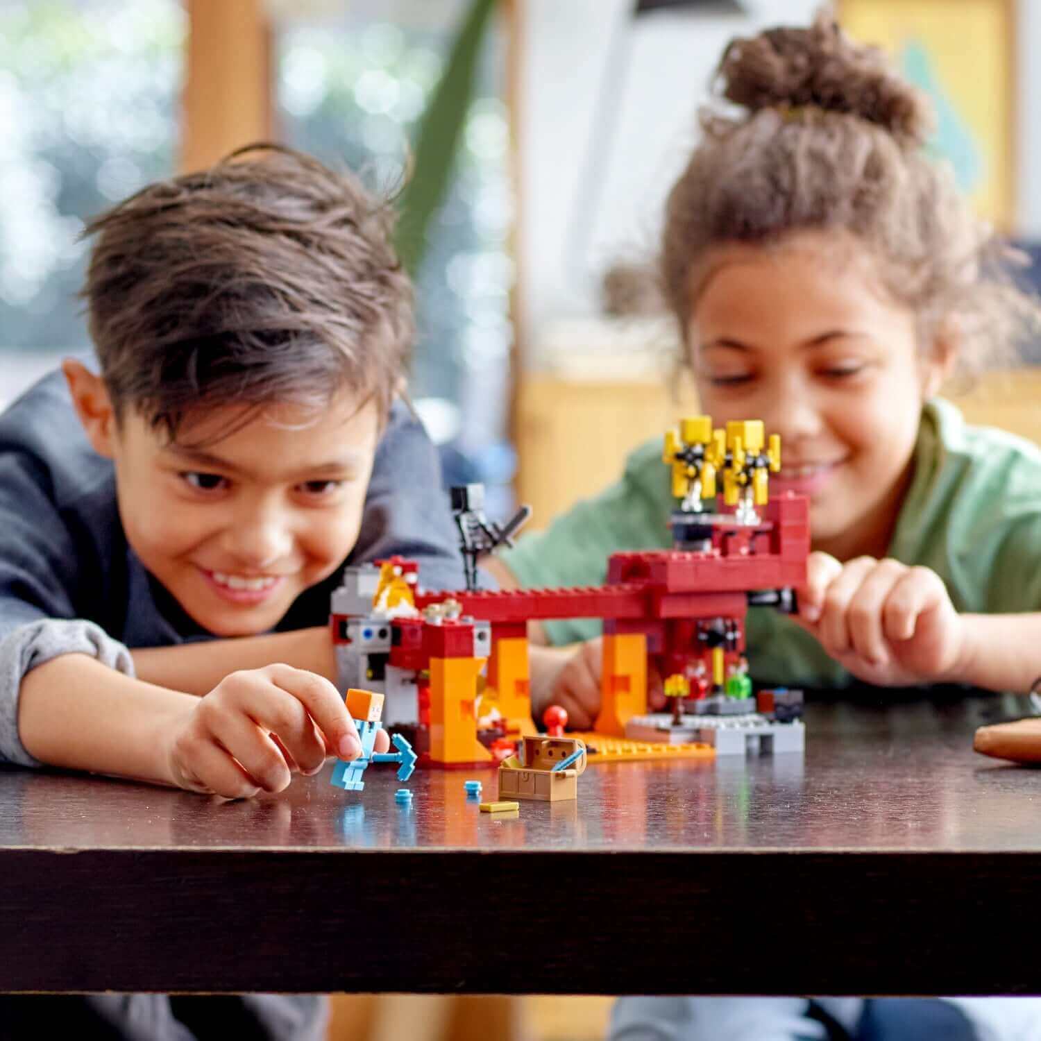 Kids enjoying the LEGO® Minecraft The Blaze Bridge Building Set with bridge and fiery lava scene.