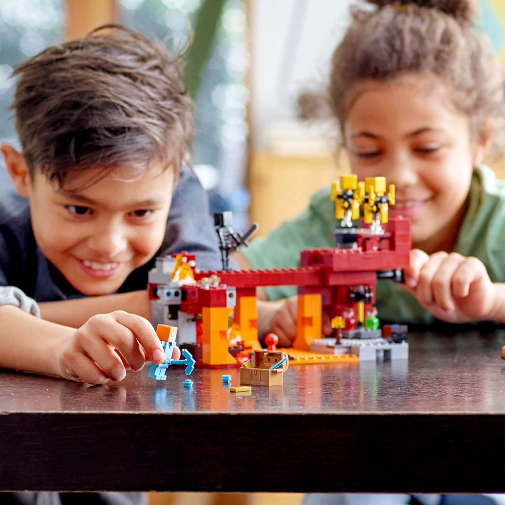 Kids playing with LEGO® Minecraft The Blaze Bridge set 21154, featuring a fiery bridge and Minecraft characters.