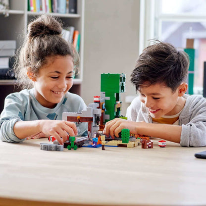 Kids building with LEGO® Minecraft The Creeper Mine set, featuring Creeper statue and minecart.