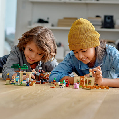 Kids playing with LEGO® Minecraft The Illager Raid set, building a colorful village with figures and a Ravager.