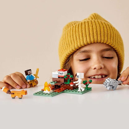 Child playing with LEGO® Minecraft The Taiga Adventure Set 21162, featuring characters and fox in a snowy biome.