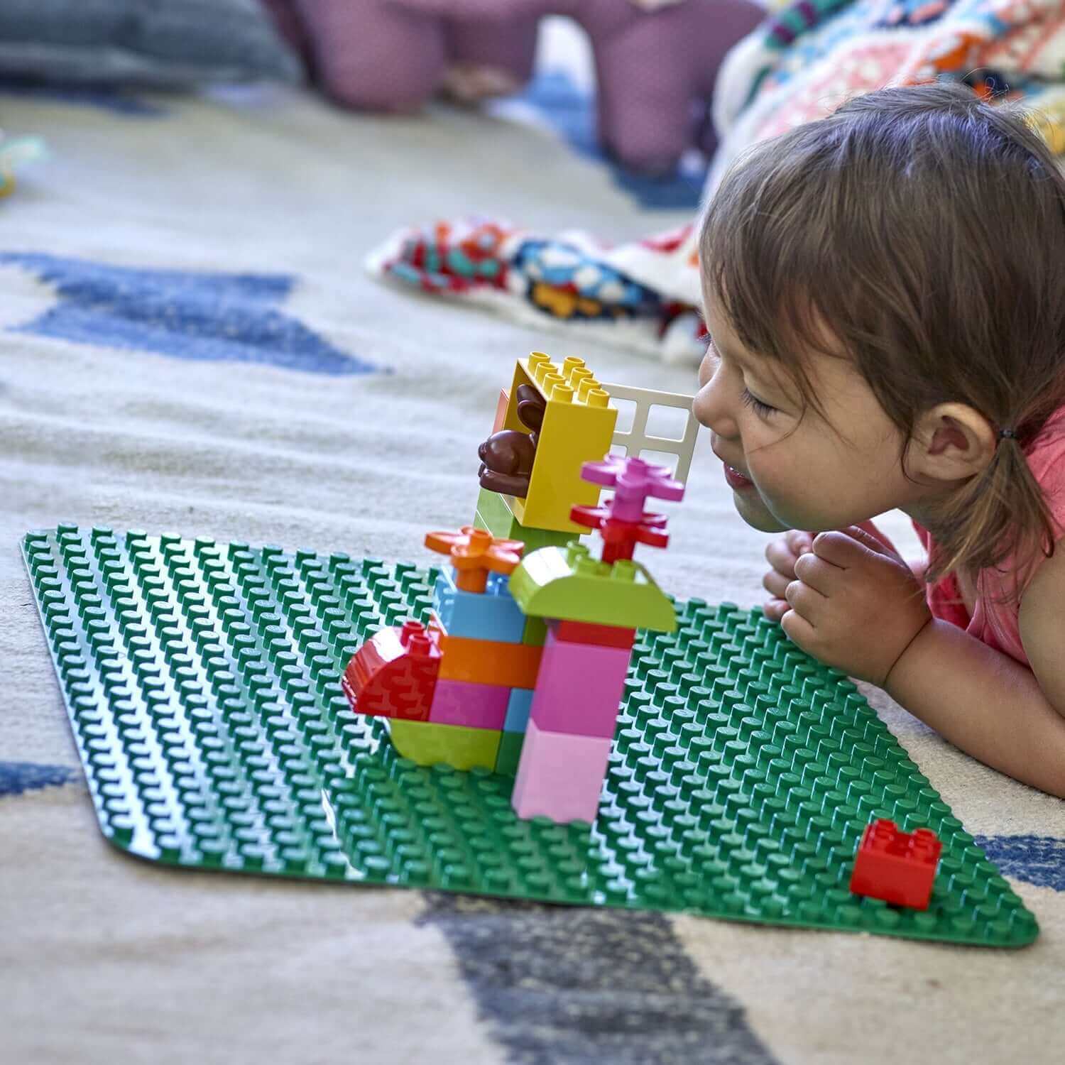 Child playing on LEGO® DUPLO Large Green Building Plate 2304, creating colorful structures and enjoying imaginative play.