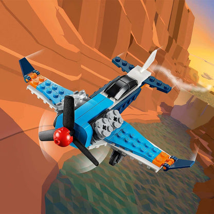 LEGO Creator 3in1 Propeller Plane Set 31099 flying near cliffs, showcasing a vibrant blue and orange design.