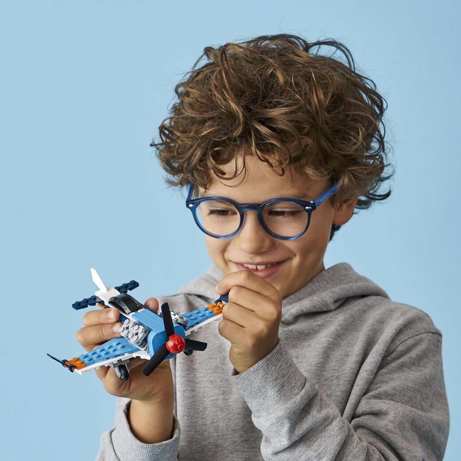 Child enjoying the LEGO® Creator 3in1 Propeller Plane Set 31099, playing with a colorful toy airplane.
