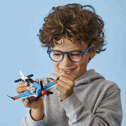 Child with curly hair smiling while playing with LEGO® Creator 3in1 Propeller Plane Set 31099.