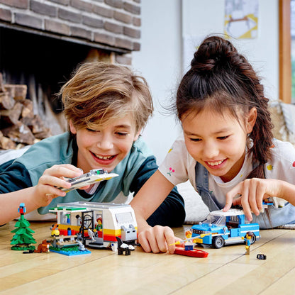 Kids playing with the LEGO® Creator 3in1 Caravan Family Holiday set, building a camper van and lighthouse.