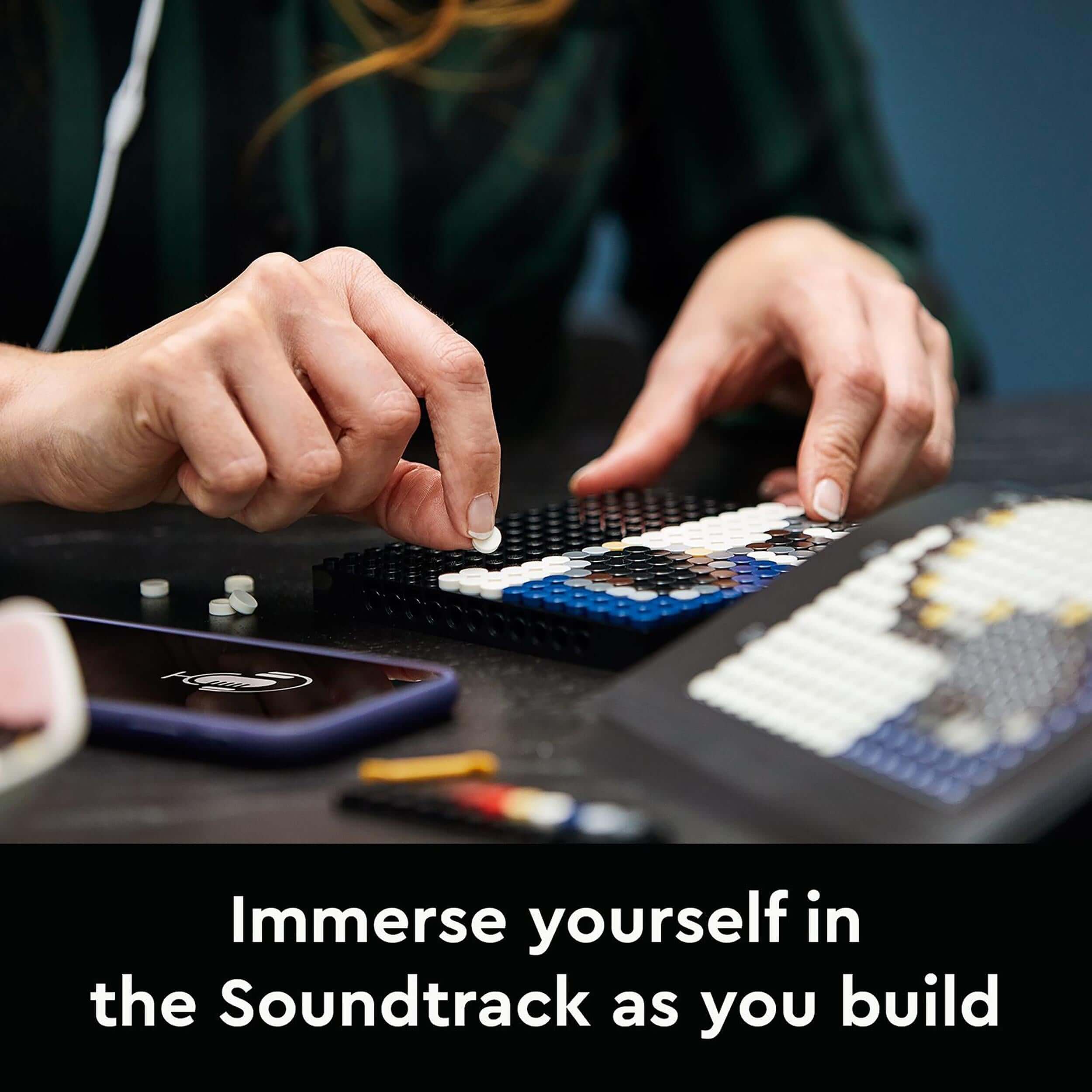 Person assembling LEGO® Disney Mickey Mouse art while listening to the soundtrack, enjoying a creative experience.