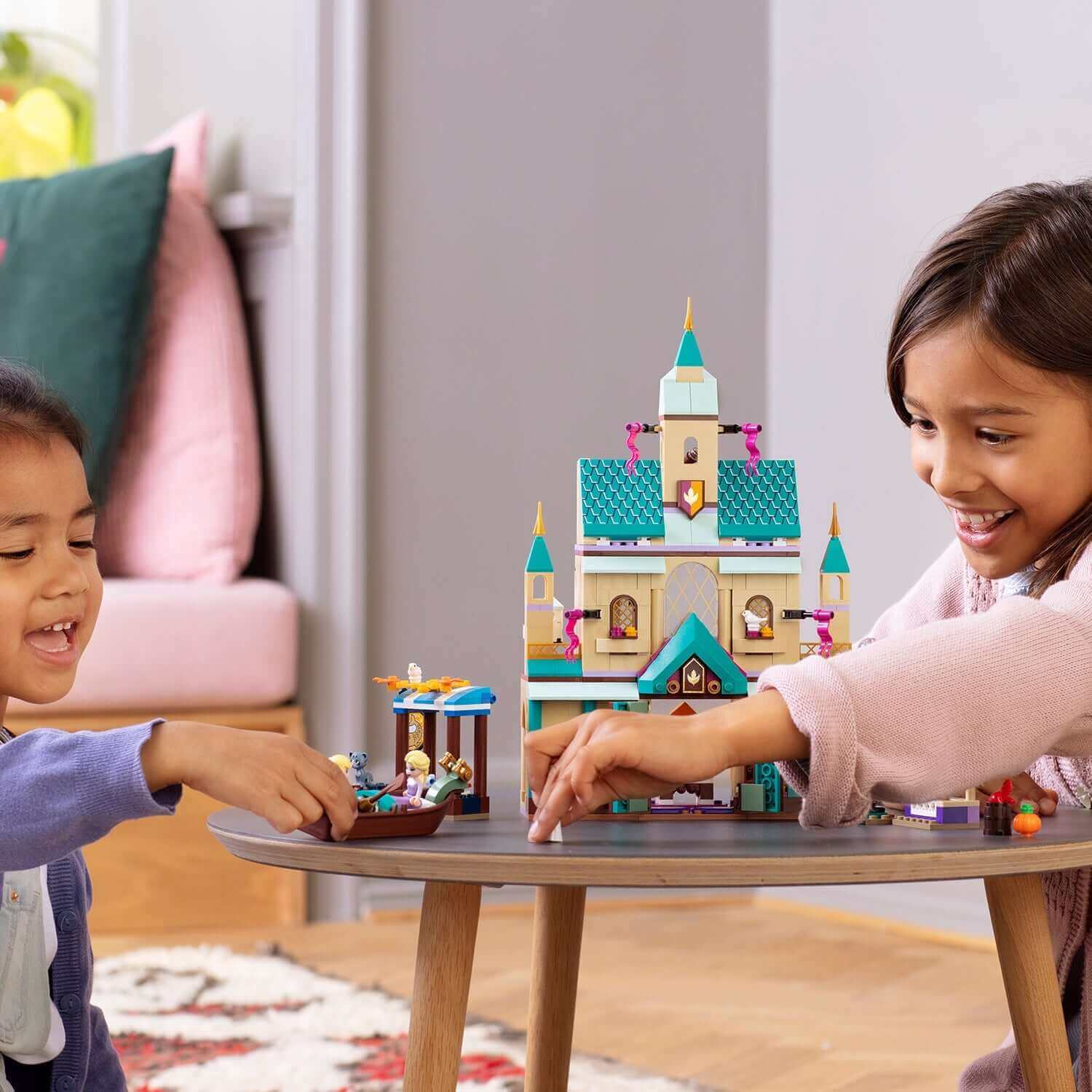 Kids playing with LEGO® Disney Frozen II Arendelle Castle Village 41167 set, featuring Anna and Elsa.