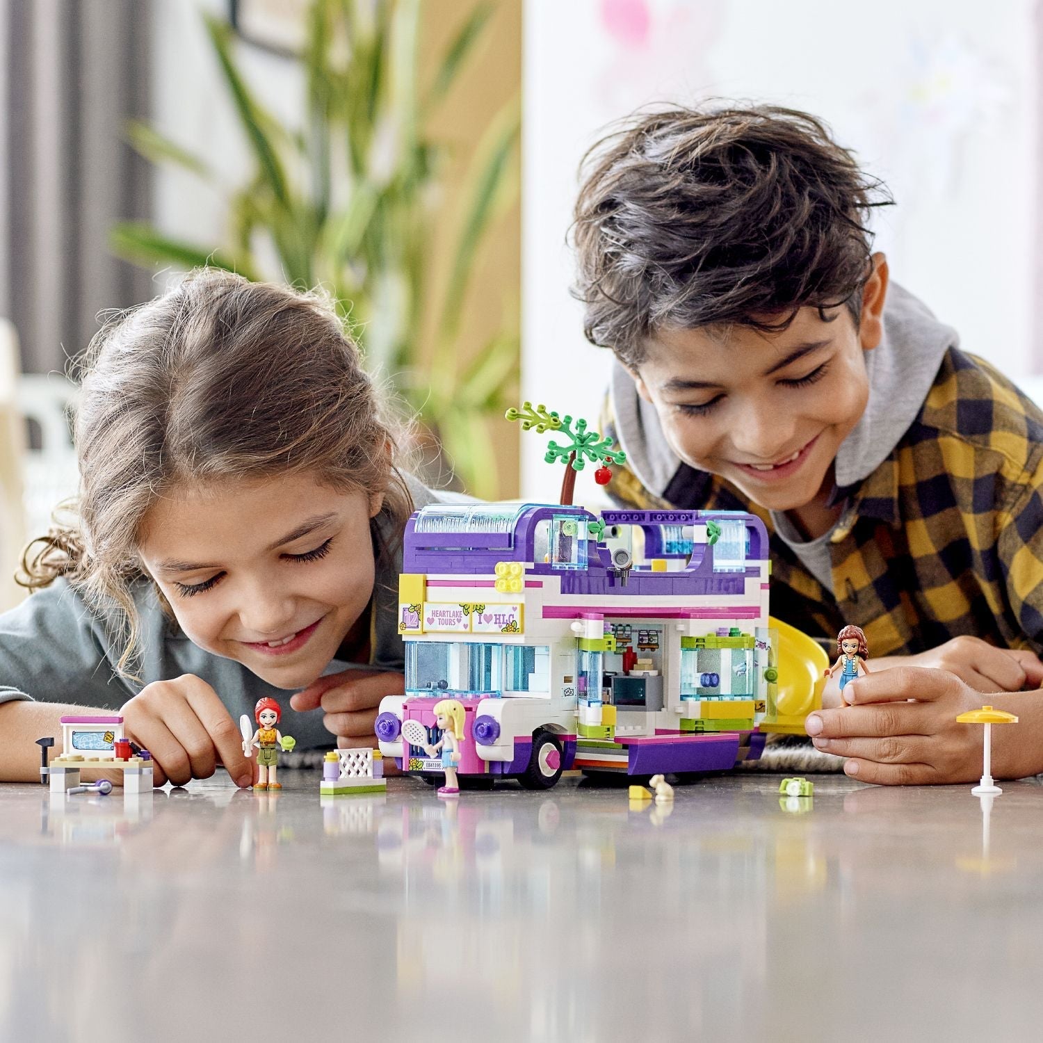 Two children playing with LEGO® Friends Friendship Bus Toy 41395 featuring a swimming pool and creative accessories.