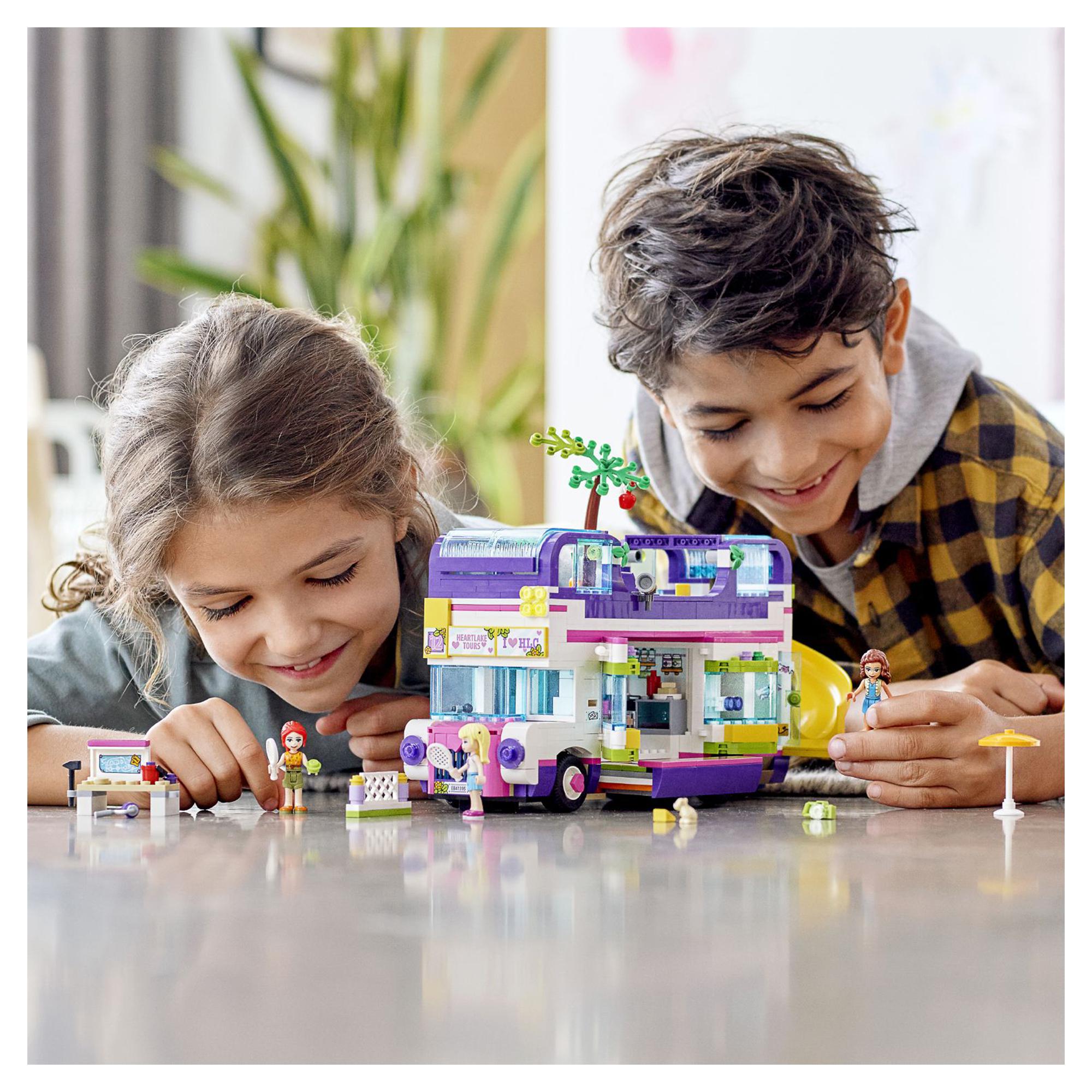Two children enjoying LEGO® Friends Friendship Bus Toy 41395, featuring a swim pool and vintage-style design.