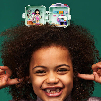 Child smiling with LEGO Friends Emma’s Fashion Cube Play Set 41668, showcasing creativity and play.