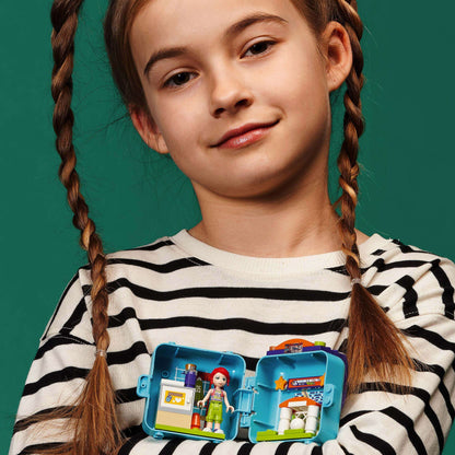 Girl showing LEGO® Friends Mia’s Soccer Cube playset, ideal for young football fans and travel. Portable play fun!