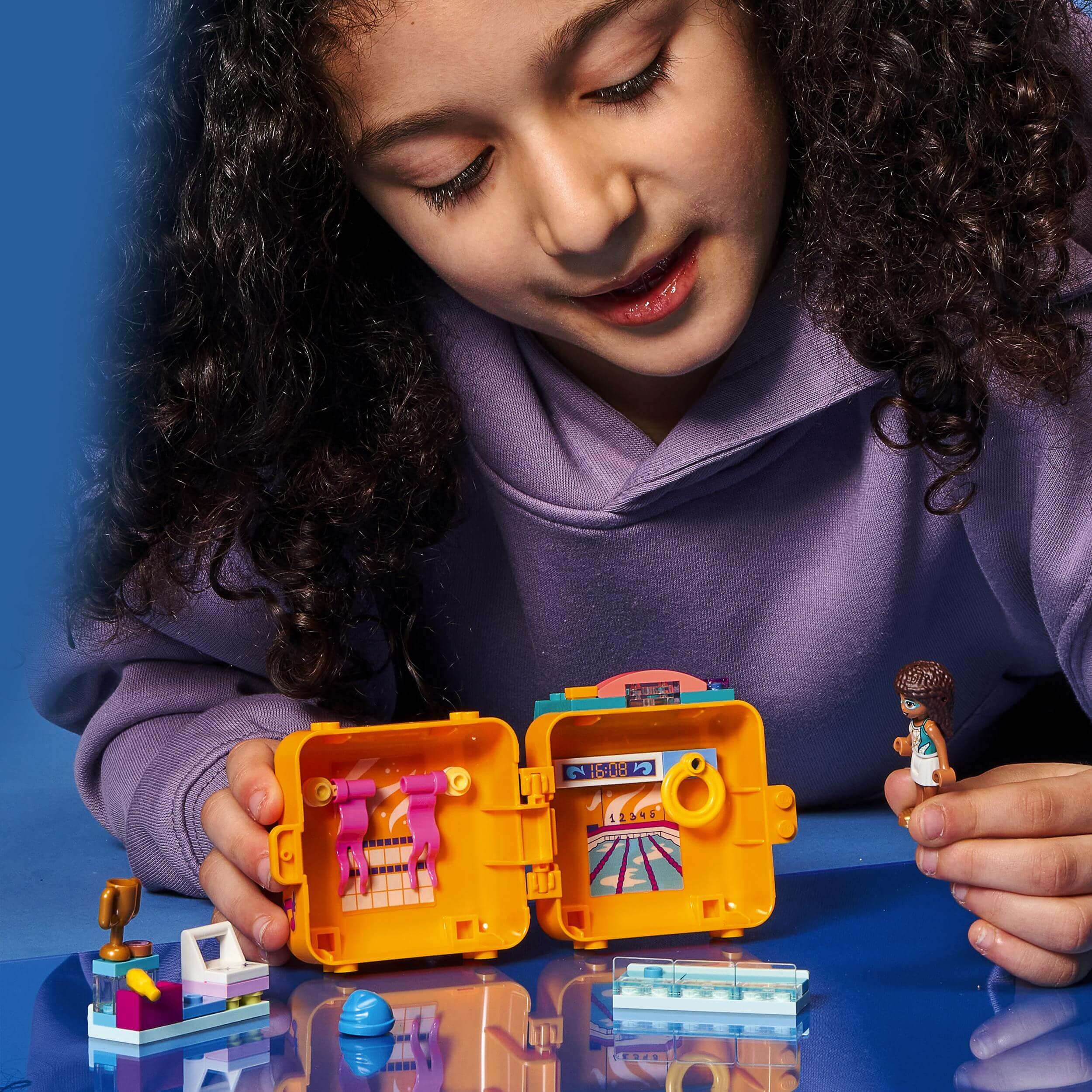 Girl exploring LEGO® Friends Andrea's Swimming Cube Play Set 41671 while playing with minifigure and accessories.