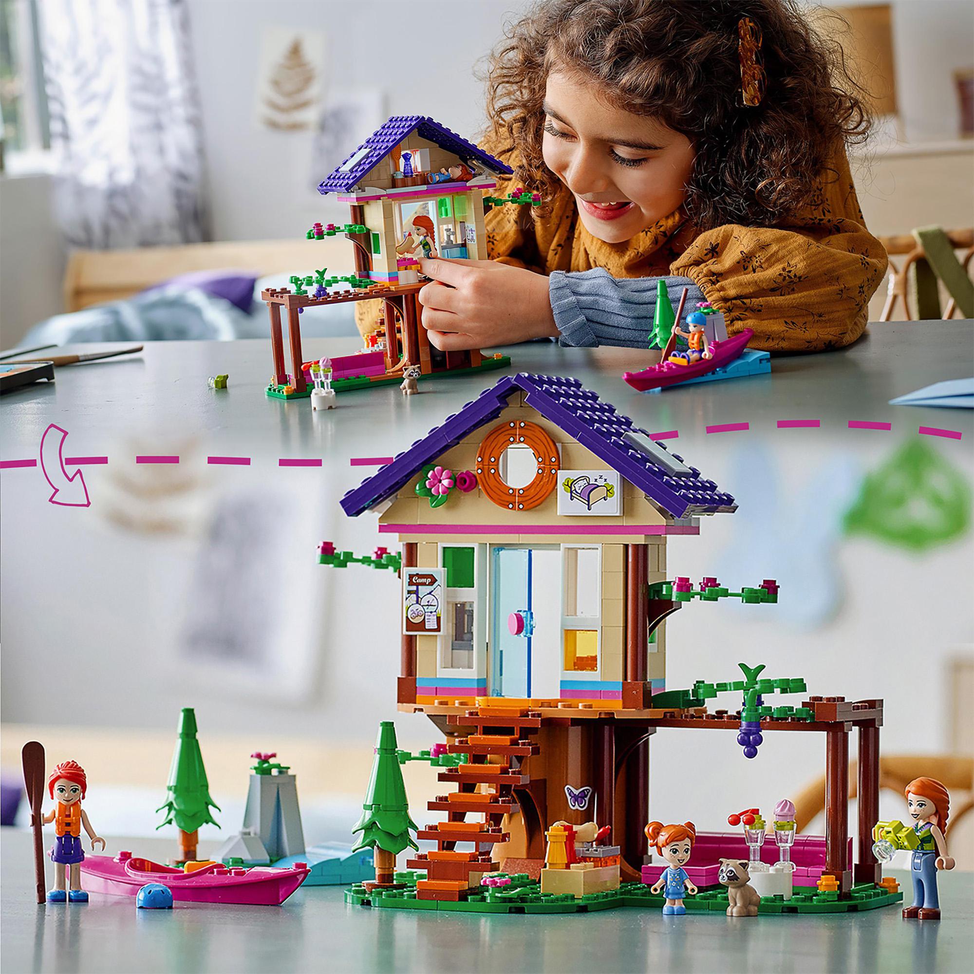 Child playing with LEGO® Friends Forest House Treehouse Set 41679, featuring nature-themed elements and characters.