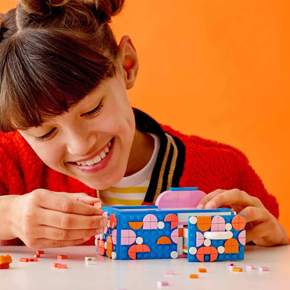 Child engaged in crafting with LEGO® DOTS Desk Organiser, adding colorful tiles to personalize the storage box.