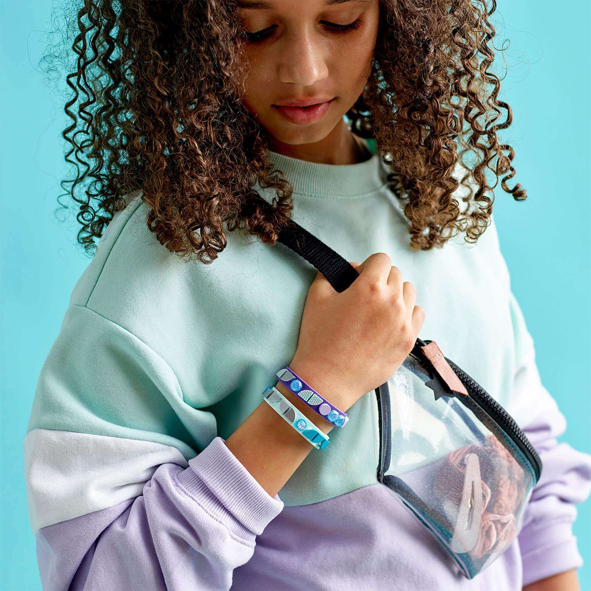 Girl wearing LEGO® DOTS Mermaid Vibes Bracelets while holding a stylish bag, showcasing colorful tiles and creativity.