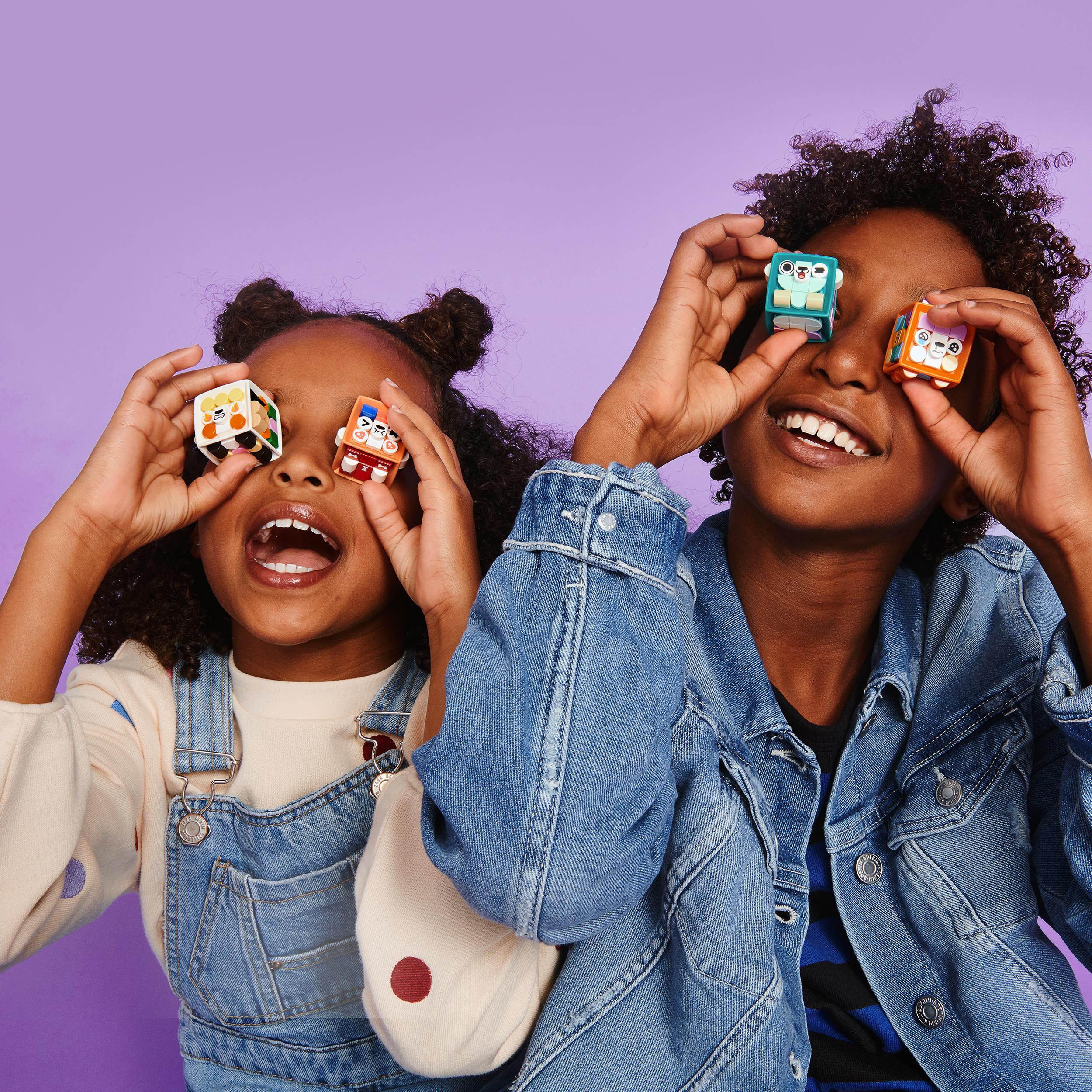 Kids holding colorful LEGO® DOTS tiles against a purple background, showcasing creativity and fun in crafts.