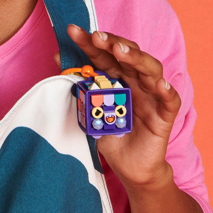 Child holding LEGO® DOTS Bag Tag Dragon featuring colorful tiles and a dark-purple cube, perfect for customizable accessories.