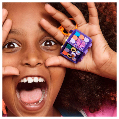 Excited child holding LEGO® DOTS Bag Tag Dragon set, showcasing vibrant customizable tiles and purple cube design.