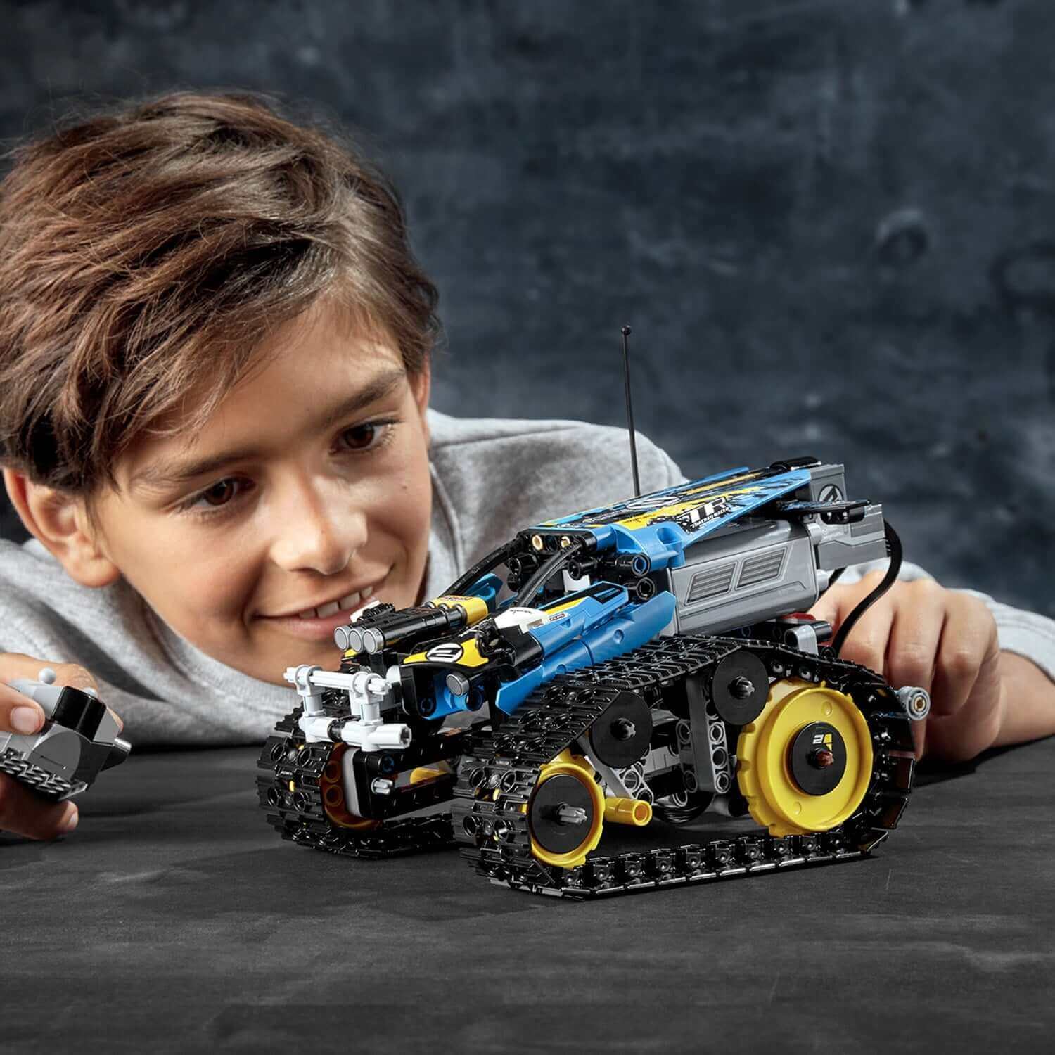 Child playing with LEGO® Technic Stunt Racer RC Car Toy 42095, showcasing fun and creativity in building and racing.
