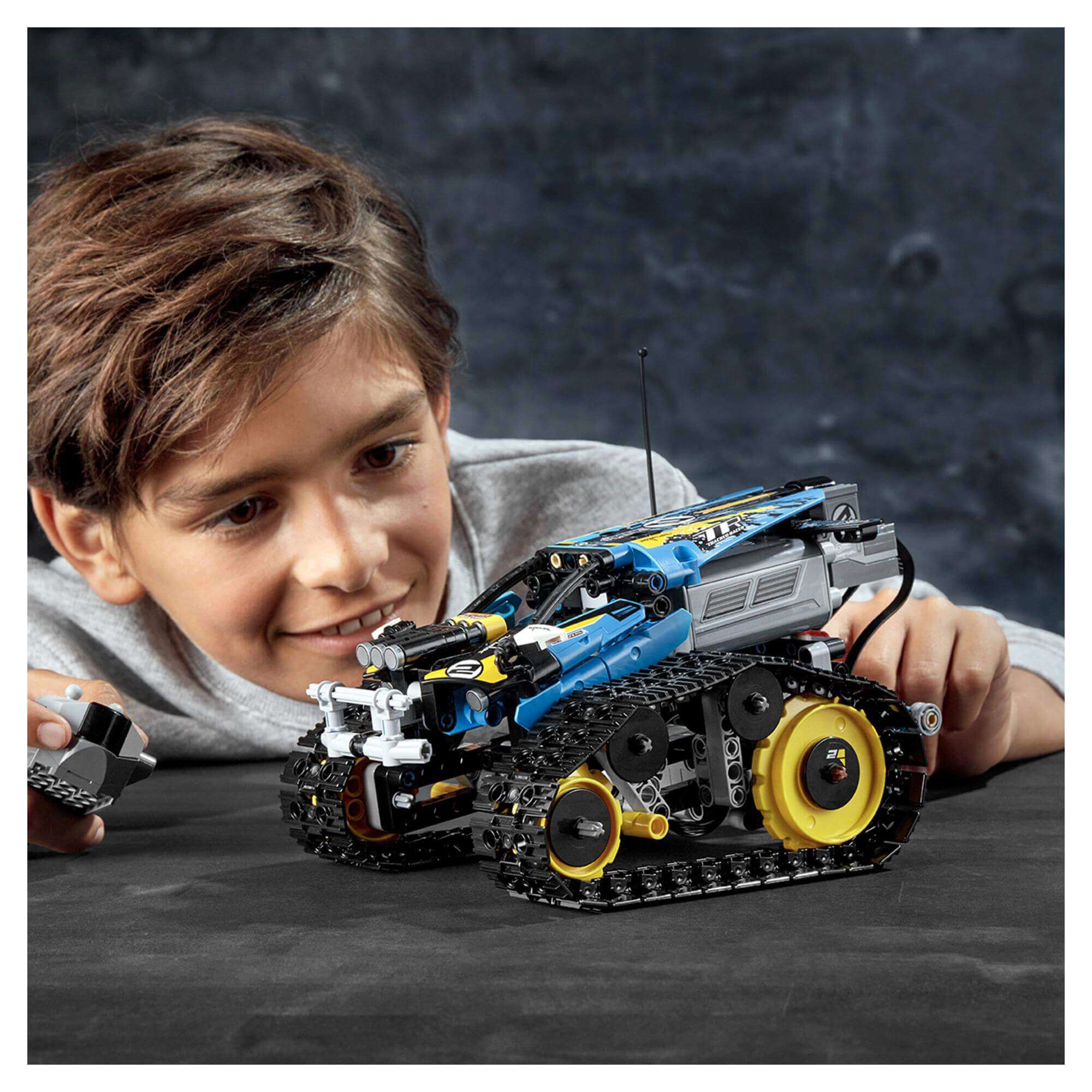 Child playing with LEGO® Technic Stunt Racer RC Car Toy 42095, showcasing fun and creativity in building.