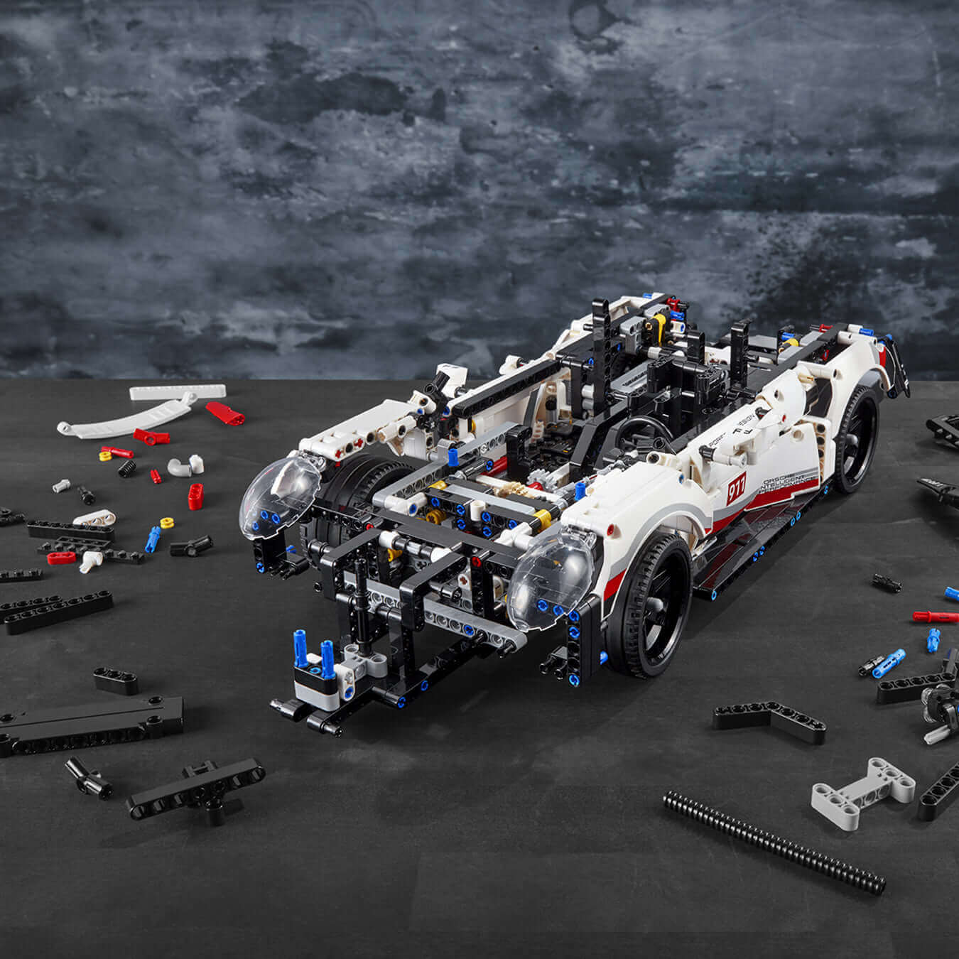 LEGO Technic Porsche 911 RSR model car set, showcasing realistic details and parts on a workspace.