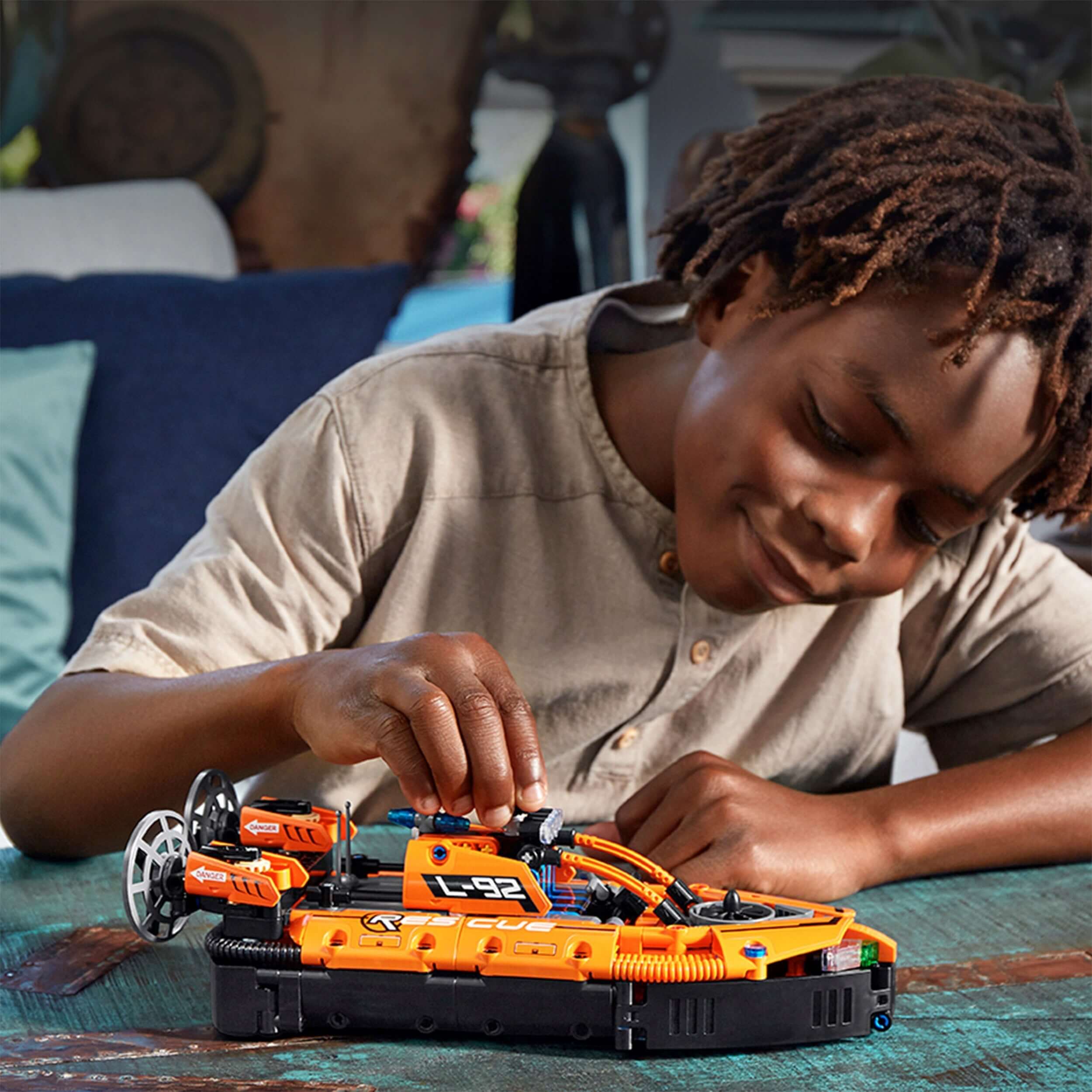 Child assembling LEGO® Technic Rescue Hovercraft model toy 42120, showcasing intricate design and creativity.