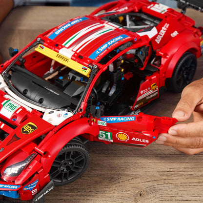 Detailed LEGO Technic Ferrari 488 GTE AF Corse #51 model being built by hands on a wooden table.