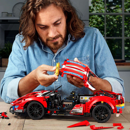 Person assembling the LEGO Technic Ferrari 488 GTE AF Corse #51 model set 42125 on a table.
