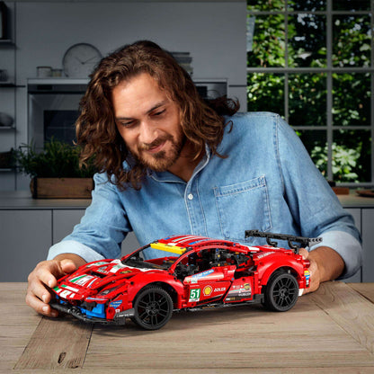 Person admiring the LEGO® Technic Ferrari 488 GTE AF Corse #51 model set 42125 in a bright kitchen setting.